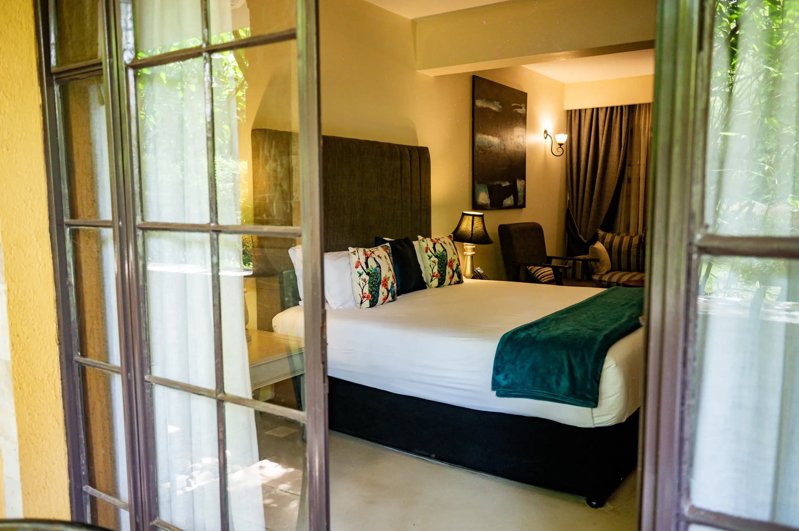 The bedroom of a Deluxe Suite at The Emin Pasha Hotel & Spa seen through its French doors