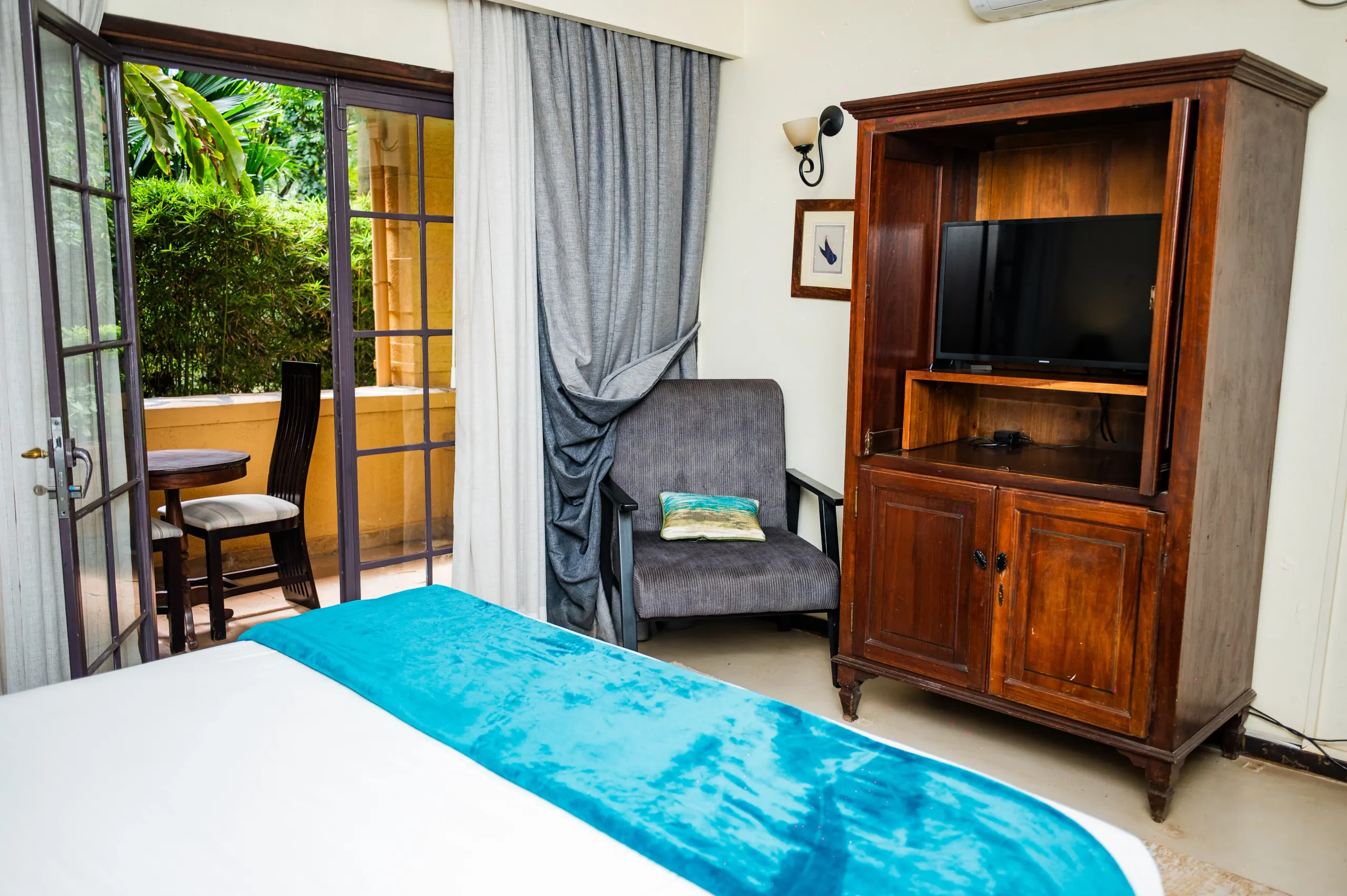 The television cabinet in a Deluxe Room at The Emin Pasha Hotel & Spa, garden doors open beyond
