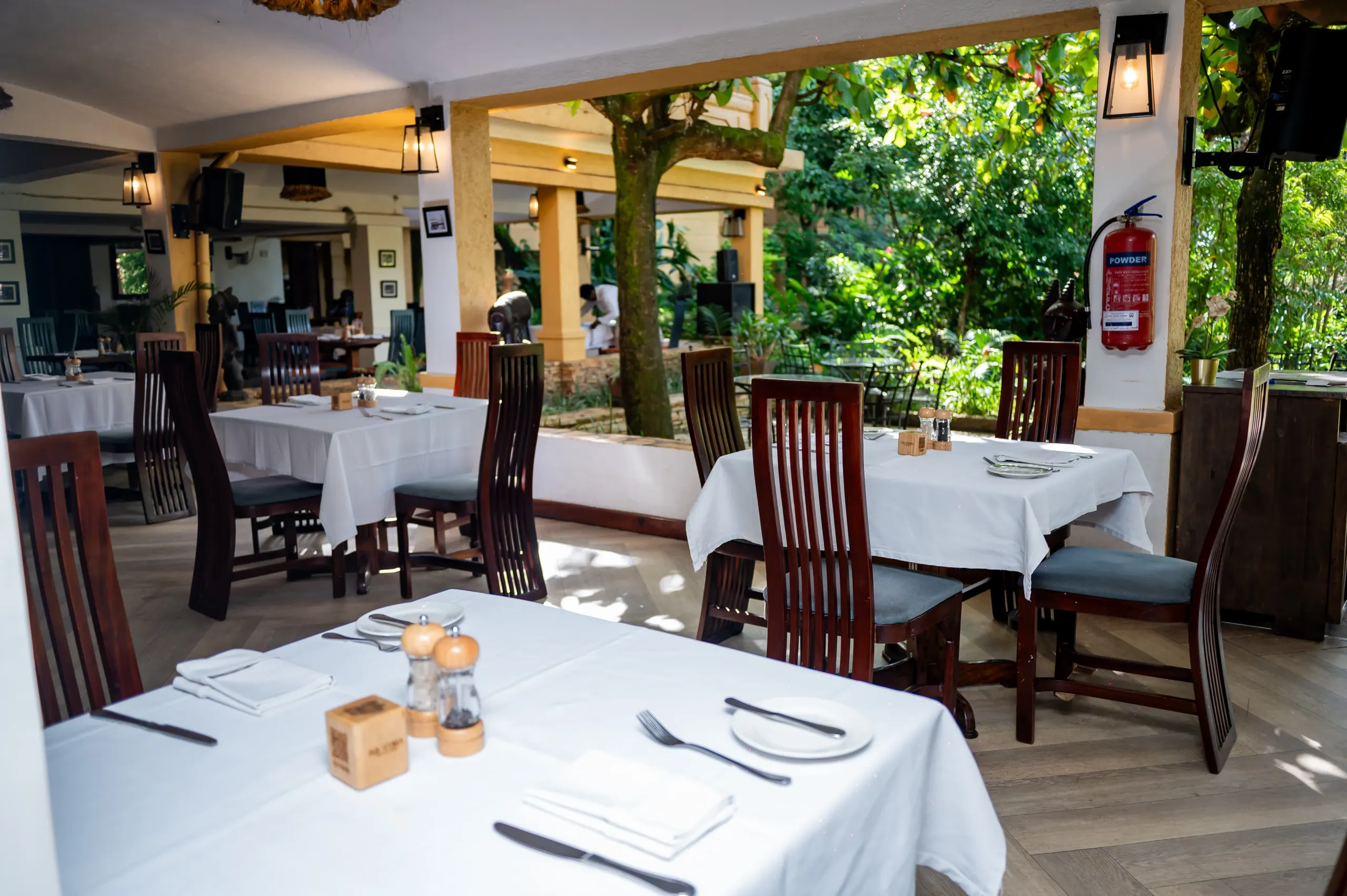 Equatoria's tables along the open side, under the tree canopy
