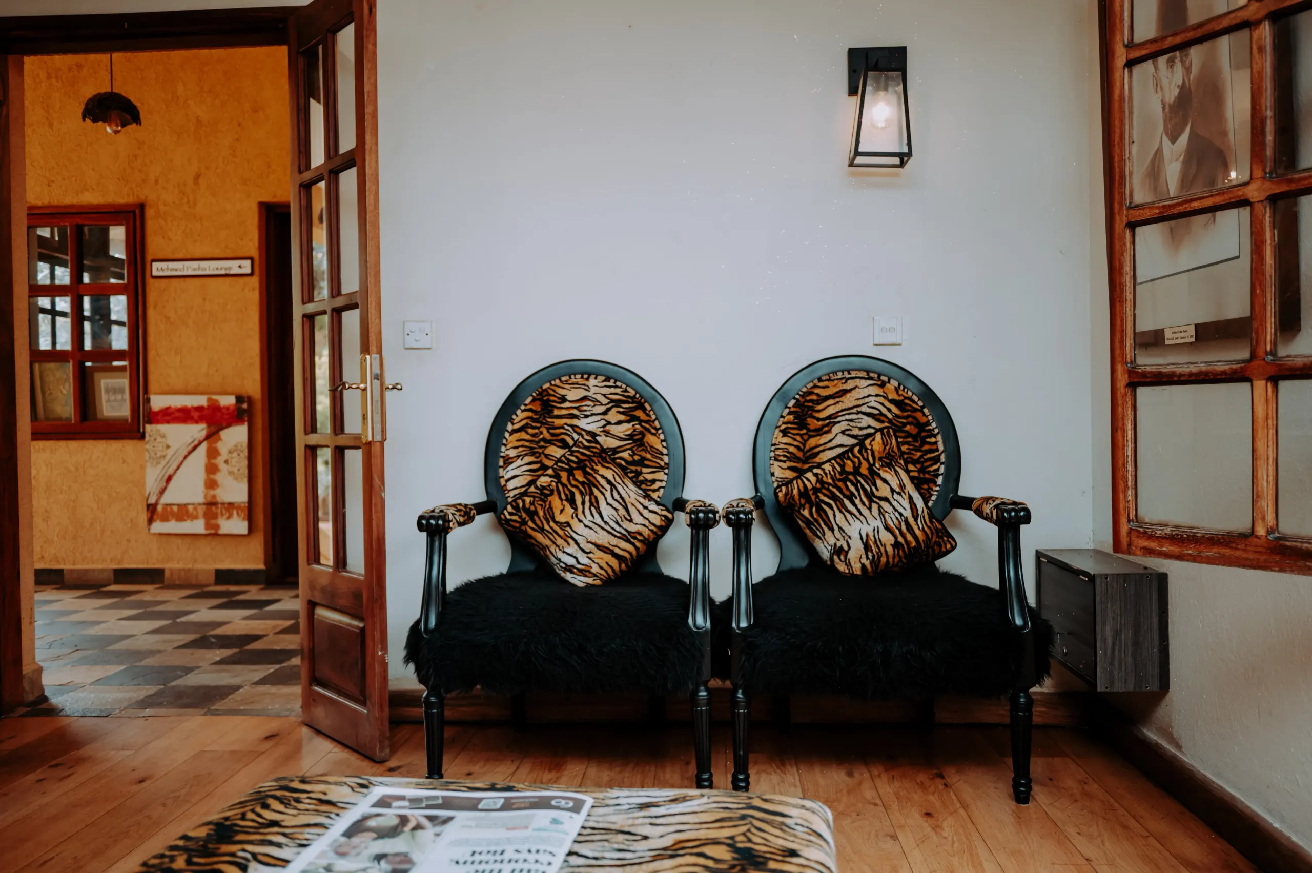 Two patterned waiting chairs beside the doorway through to the lounge