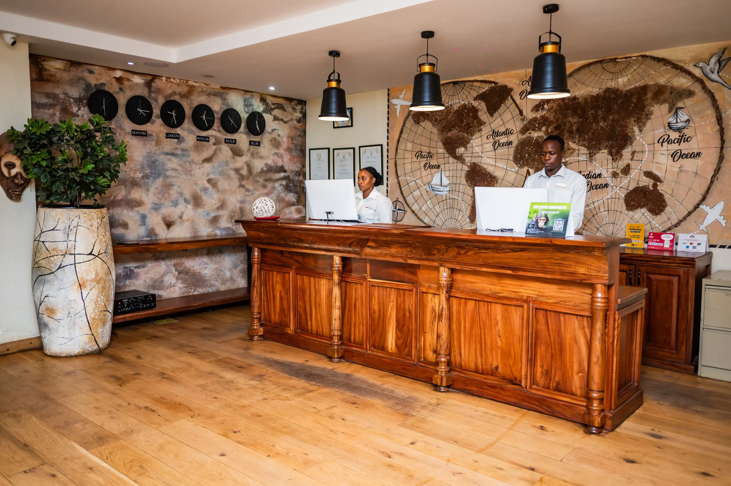 The reception desk at The Emin Pasha Hotel & Spa, two receptionists before a painted world map