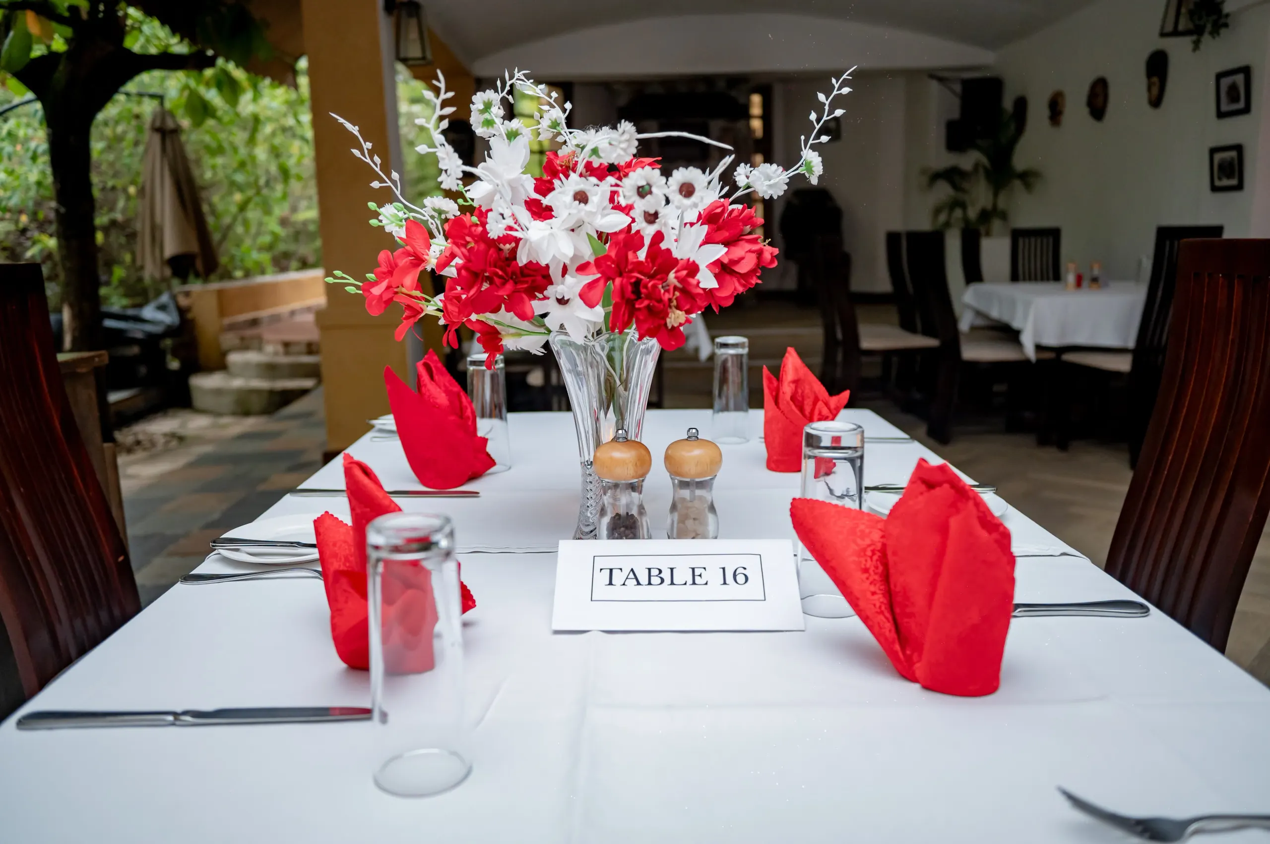 A laid table with red napkins, a candle and a printed table number